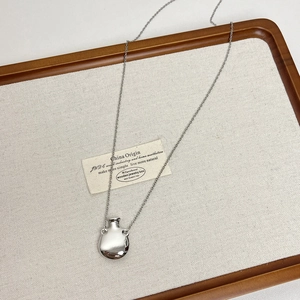 Detailed macro view of a silver perfume bottle pendant on a burlap display tray