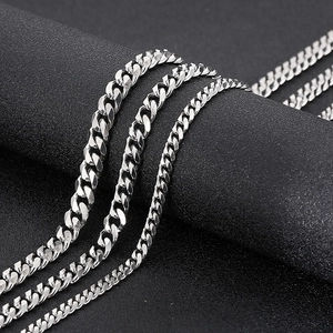 Macro shot of silver curb chains in different widths on a matte black display