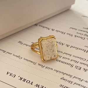 Detailed shot of rectangle marble stone ring with gold base on a white book