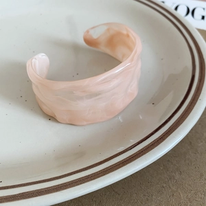 Macro shot of pink marble texture on an acrylic open bangle placed on a ceramic tray