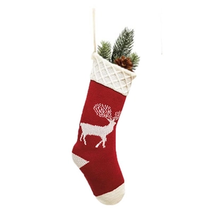 Detail of red knit Christmas stocking featuring white reindeer pattern and pine decorations