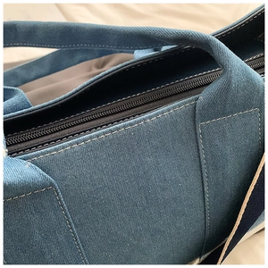 Detail view of the top zipper closure and stitching on blue canvas tote bag