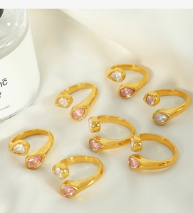 Group of 7 gold-plated rings with drop-shaped pink and clear crystals on white silk