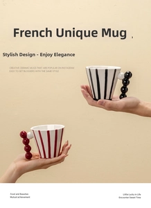 Detailed view of handmade ceramic mug featuring a unique spherical ball handle and stripe pattern