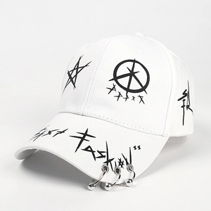 Detail of white baseball cap featuring black punk graffiti and three silver metal rings on brim