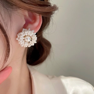 Macro view of model wearing a large pearl flower earring with gold metal accents