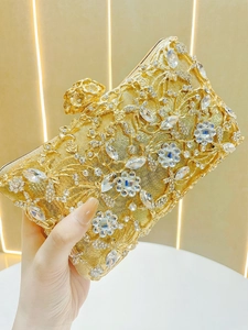 Detail of gold evening clutch featuring intricate metal flowers and crystal embellishments