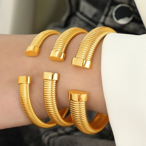 Minimalist gold spiral tubogas open cuff bracelet stacked on wrist for unisex style