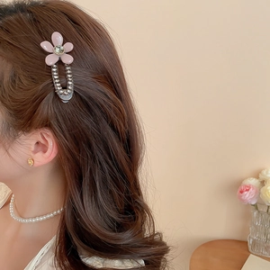 Close-up of pink flower hair clip with rhinestones worn on side hair for a sweet look