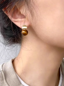 Close-up of model wearing 18k gold plated tiger eye stone stud earrings with round beads