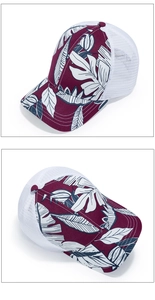 Detail view of burgundy baseball cap featuring tropical leaf prints and white mesh panels