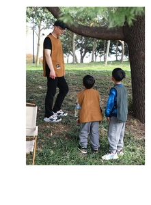 Close-up of khaki waterproof art apron and grey pants on a child in outdoor setting