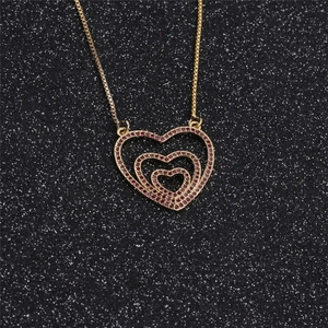 Detailed macro view of triple-layered heart pendant with pink zircon and gold box chain
