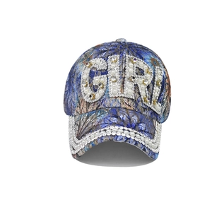 Detailed close-up of Pearl and Rhinestone GIRL letters on the blue floral baseball cap