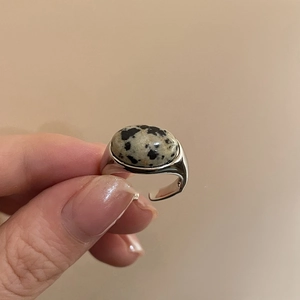 Detailed close-up of oval spotted stone inlay on a silver adjustable open ring