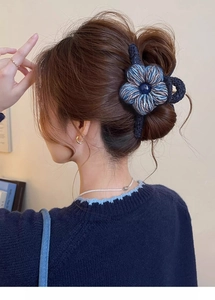 Gros plan d'une pince à cheveux fleur tricotée bleue sur une coiffure chignon élégante