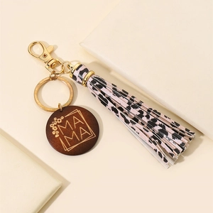 Close-up of wooden MAMA charm with leopard print tassel on a golden keychain