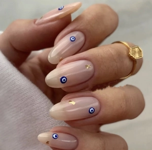 Close-up of evil eye nail stickers with gold foil flakes on a natural base manicure