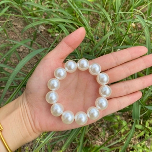 Elegant white faux pearl bracelet with elastic band shown in a natural outdoor setting