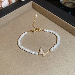 Detail view of pearl bracelet with a gold butterfly pendant on a jewelry tray