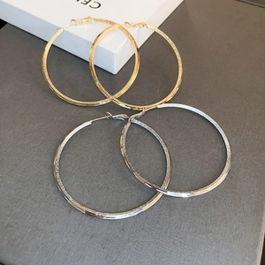 Detail of large textured gold and silver hoop earrings with sparkling metallic finish