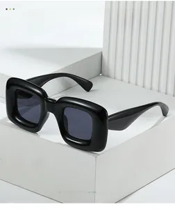 Detail of trendy Y2K black oversized square sunglasses on a minimalist white display stand