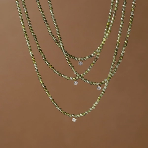 Detail of olive green faceted beads necklace with round sparkling zircon pendant crystals