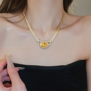Close-up of vintage gold woven necklace featuring a radiant oval yellow gemstone