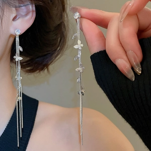Gros plan de boucles d'oreilles pampilles argentées avec papillons en zircon et chaînes
