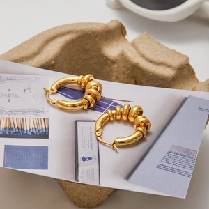 Detail view of gold stainless steel multi-hoop earrings on textured studio paper
