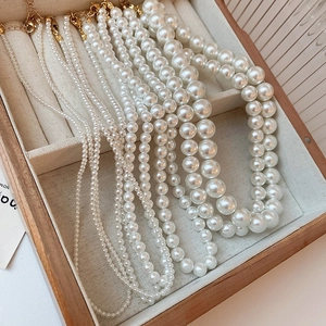 Detail view of assorted pearl sizes and golden lobster clasps in a luxury wooden box