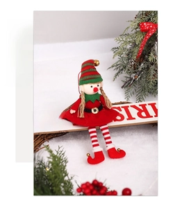 Detail of Christmas elf doll sitting on a wooden sign with knit and plush textures