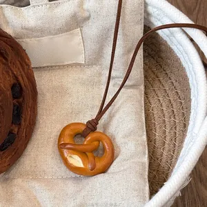Dettaglio della collana con ciondolo a forma di pretzel con trama realistica e cordino