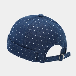 Detail of navy blue docker hat with white dots and adjustable silver metal buckle strap