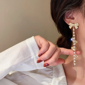 Boucles d'oreilles longues dorées avec nœuds et perles sur le portrait d'un mannequin