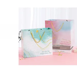 Detail of luxury pink and marble gift bags with gold handles and 'Just For You' foil stamping