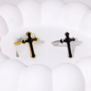 Close-up of gold and silver cross rings with black enamel on a textured white tray