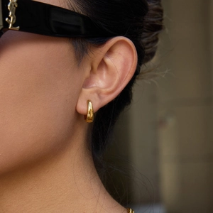Detail of minimalist 12mm thick golden hoop earring with polished mirror finish