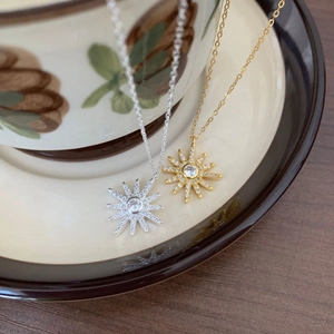 Close-up of minimalist 925 sterling silver necklaces with sunburst star pendants and gems