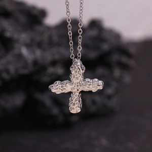 Macro shot of silver textured cross pendant with unique hammered finish on stone surface