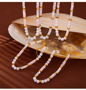 Detailed view of handmade white and pink beaded necklace set with golden metal accents