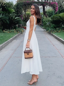 Robe midi blanche élégante sans manches avec décolleté carré et sac à main tissé dans un jardin