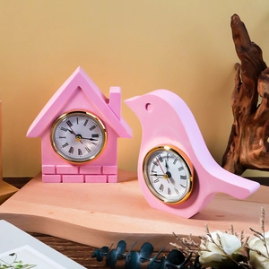 Pink Nordic bird and house shaped desk clocks with Roman numerals on wood display