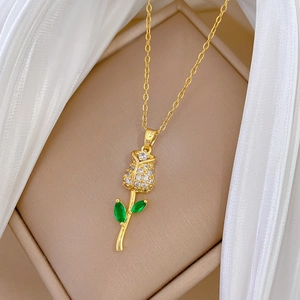 Detailed macro view of gold rose necklace pendant with sparkling crystals and green leaves