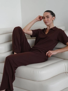 Close-up of brown knitted jacquard polo top and straight trousers on a white sofa