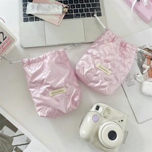 Flat lay of pink quilted drawstring bags for camera storage with heart and bow details