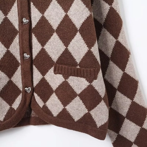 Detail of diamond pattern knit cardigan with silver heart buttons and ribbed pocket
