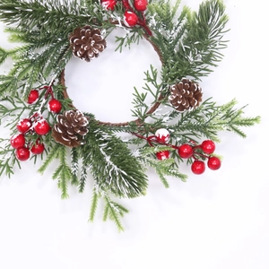 Christmas candle ring with frosted pine needles red berries and natural pine cones