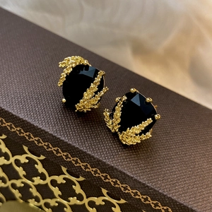 Gros plan détaillé de boucles d'oreilles épi dorées avec pierres noires sur un coffret