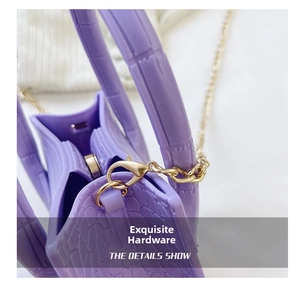 Detail shot of purple crocodile pattern handbag with gold chain strap and magnetic closure